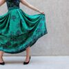 A stylish woman poses with a green patterned skirt, showcasing elegance and fashion.