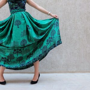 A stylish woman poses with a green patterned skirt, showcasing elegance and fashion.