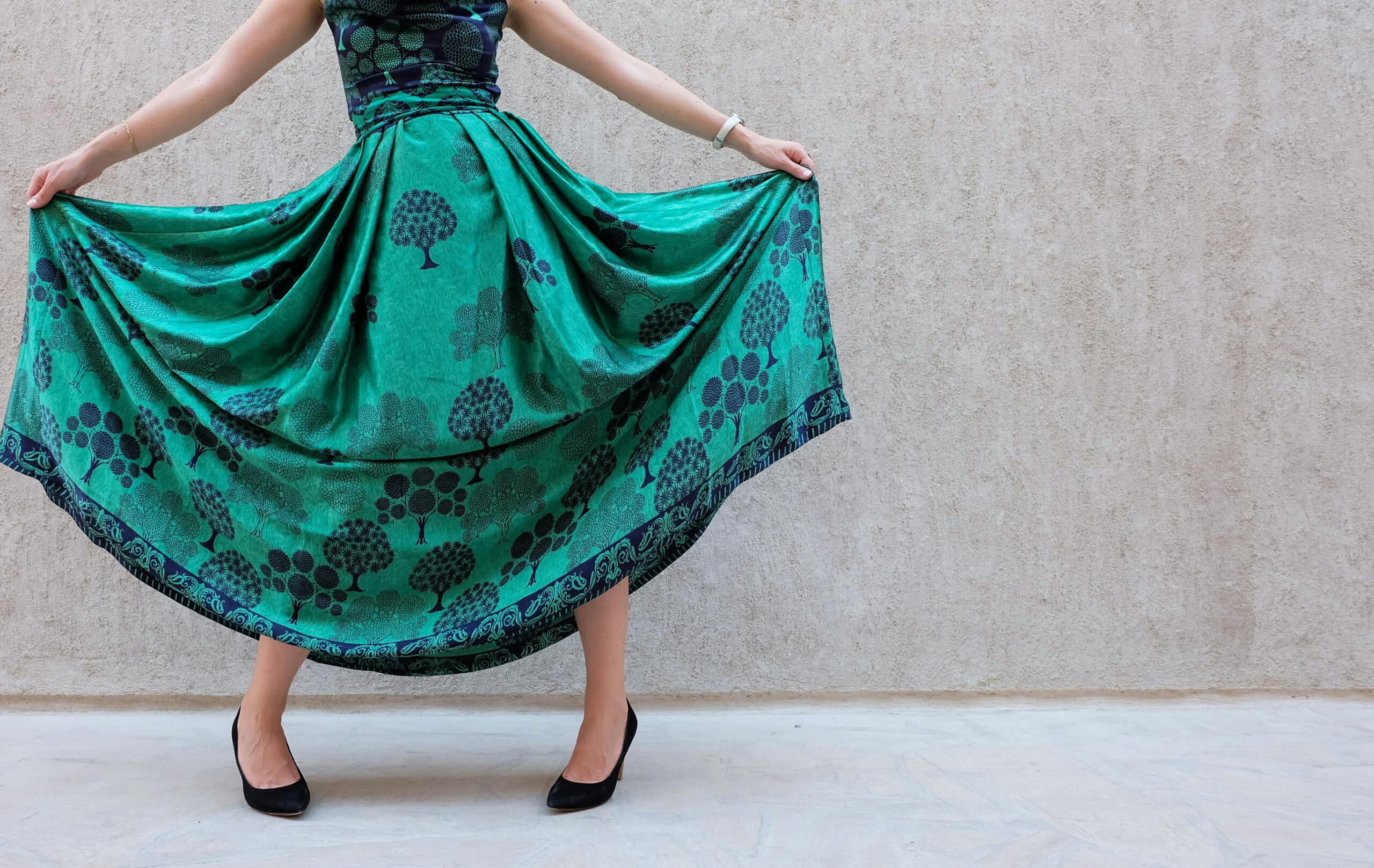 A stylish woman poses with a green patterned skirt, showcasing elegance and fashion.